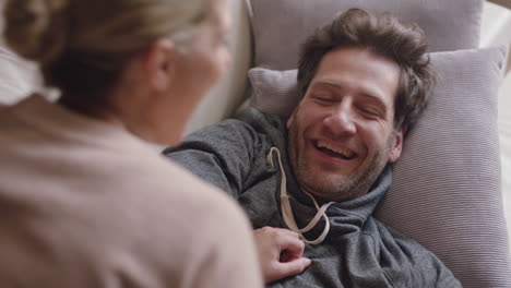 happy young couple taking photos together using camera having fun at home on sofa playfully enjoying romantic relationship photographing each other making faces