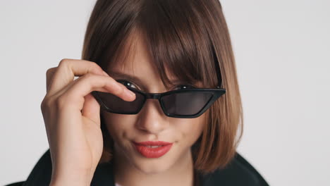 woman with red lips putting on sunglasses