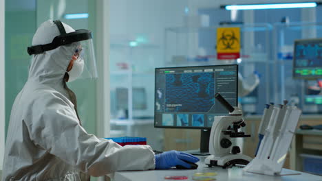 doctor with overall suit working at computer and looking at camera.