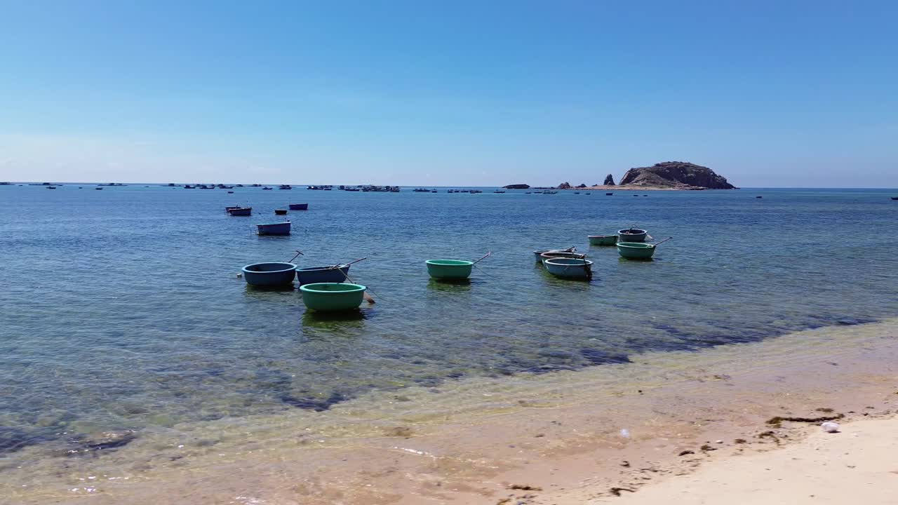 Aerial view of fishing village in Ninh Hải District, Ninh Thuận with a semi orbit drone movement showcasing traditional boats and the coastal landscape. Ninh Hải District, Ninh Thuận, Vietnam