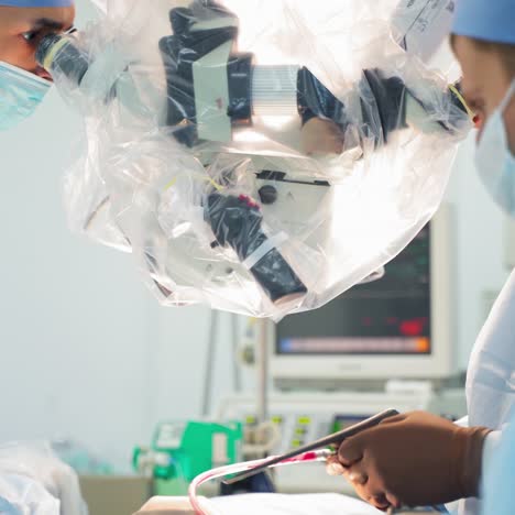 neurosurgeons in modern hospital. surgeons use medical microscope during operating process. group of doctors in medical uniform operate patient.