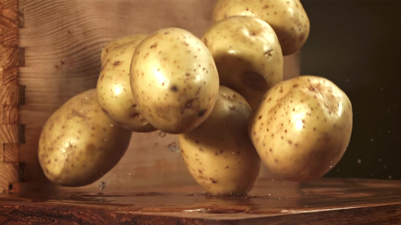 Patate fresche che cadono su una superficie di legno bagnata al rallentatore