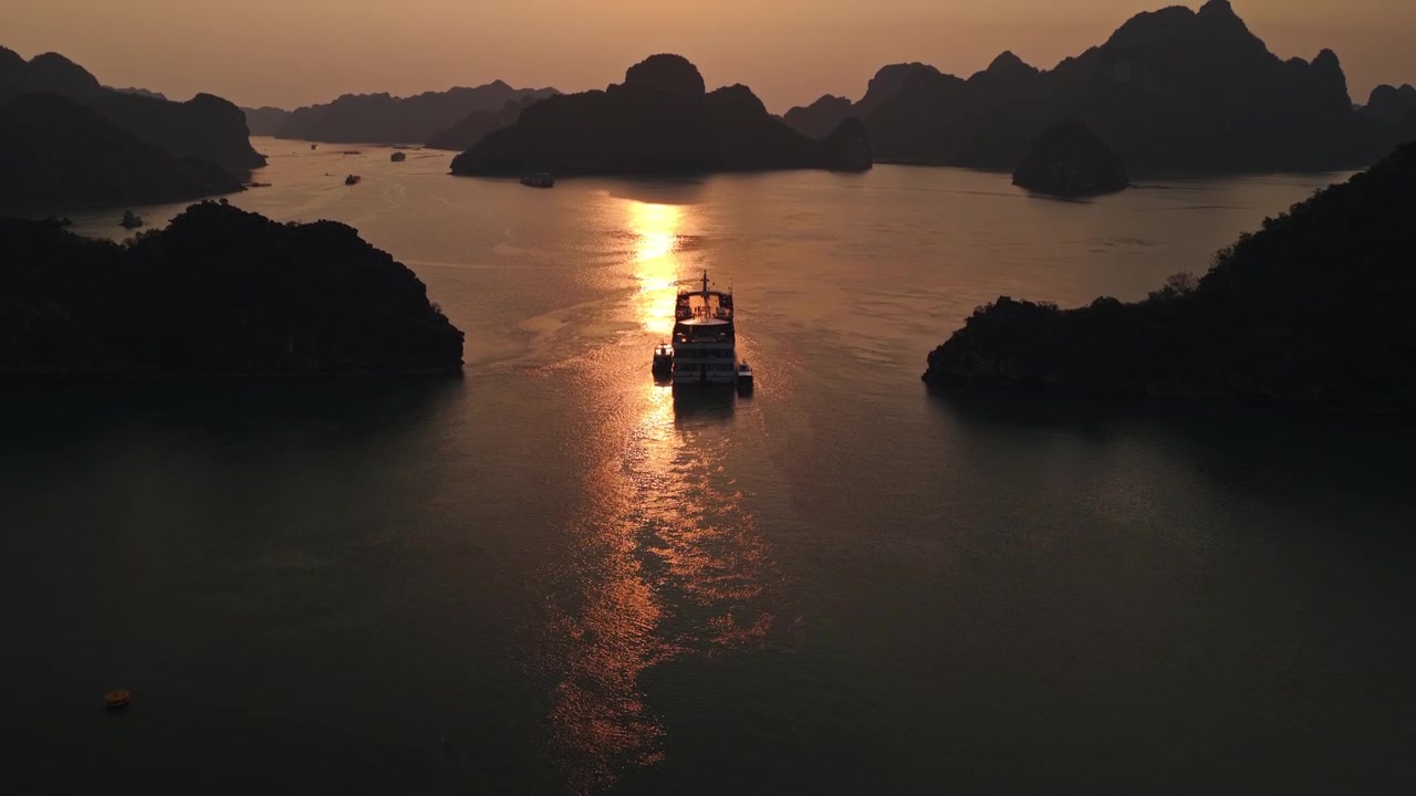 Du thuyền đang lướt qua làn nước yên bình, mờ sương của Vịnh Hạ Long vào lúc hoàng hôn ở Việt Nam - Ảnh chụp bằng drone