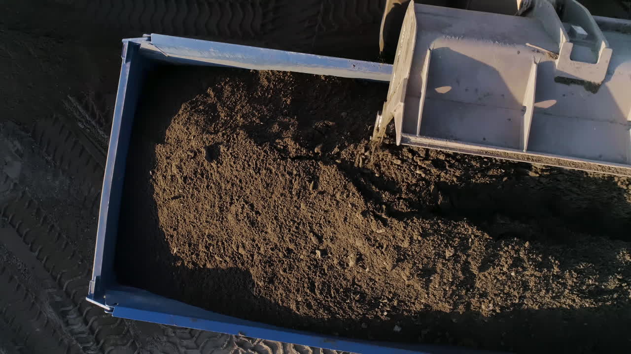Escavatore che carica terra su un autocarro ribaltabile