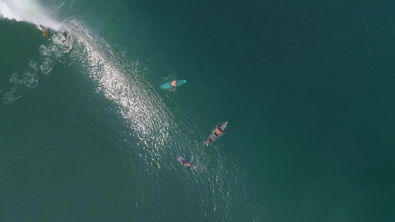 Aerial cenital cinematic shot of a surfers waiting and a surfer surfing a big tube barrel wave that creates a rainbow in Zicatela beach Puerto Escondido, Oaxaca