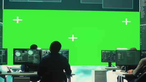 Team-of-governmental-hackers-look-at-green-screen-in-high-tech-agency-office