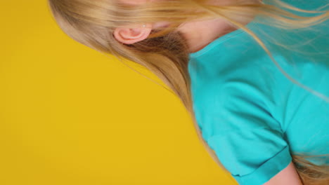 vertical video of girl with long hair laughing and spinning against yellow background