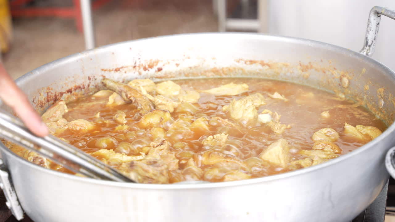 mezclar la sopa de cerdo con una cuchara grande, comida callejera en ecuador
