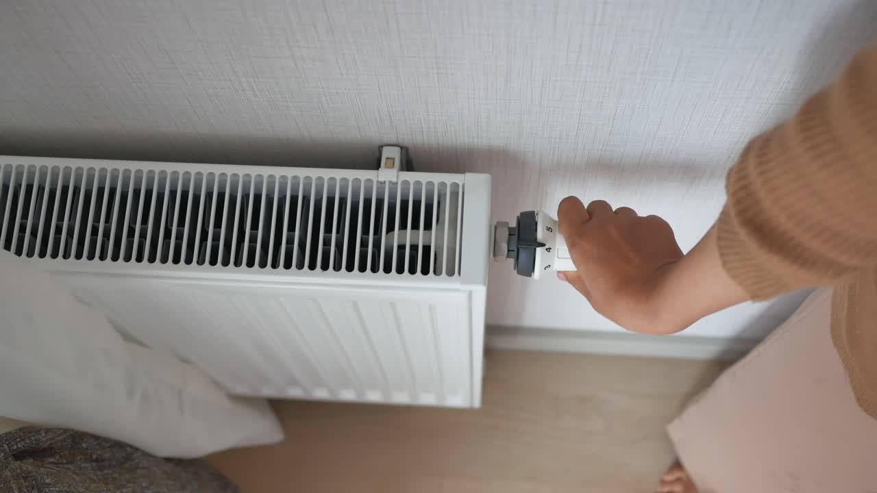 persona que ajusta el termostato en el radiador