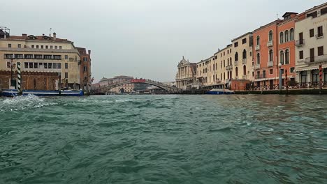 water surface pov of venice seen from ferry boat on canal grande with ponte degli scalzi bridge in background, italy