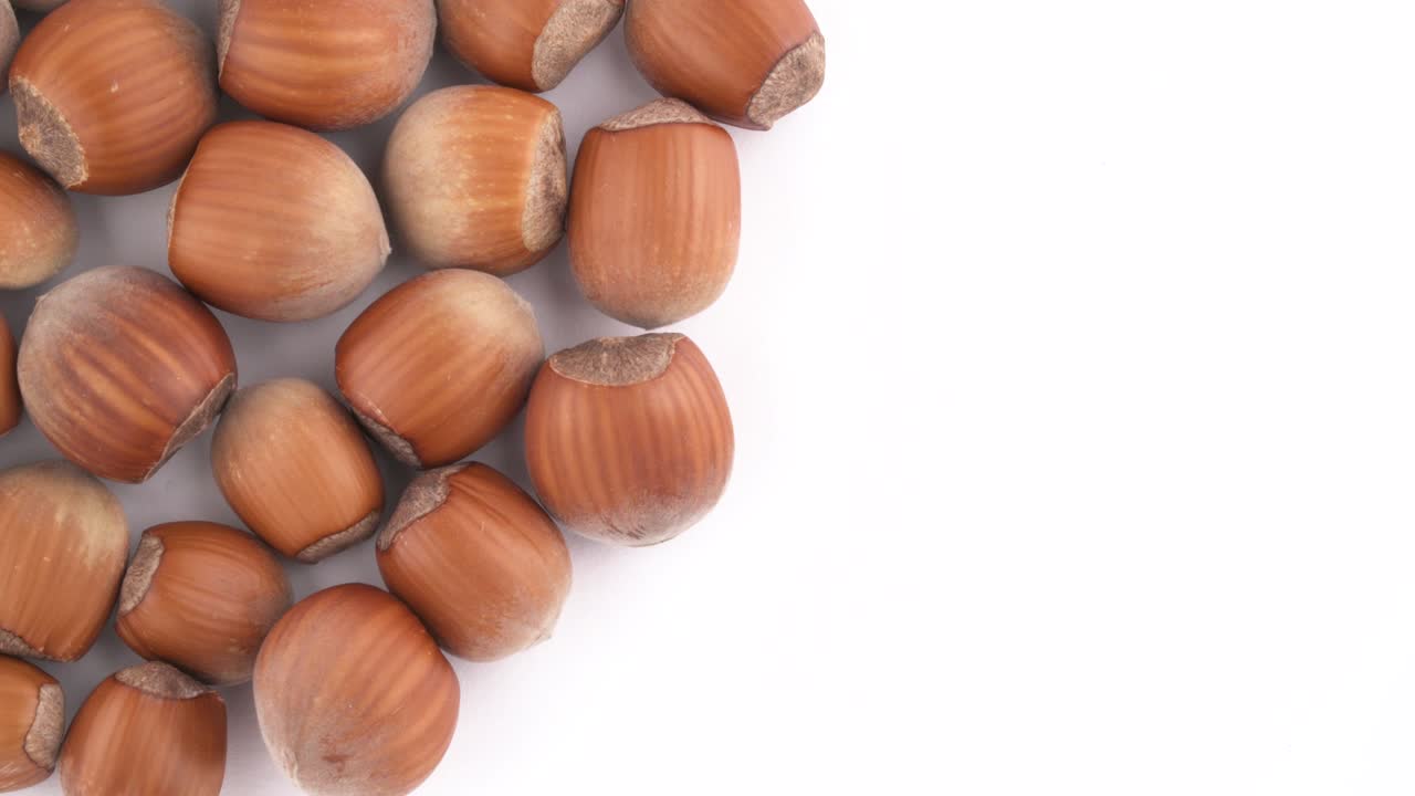 Horizontal half frame circle shaped heap of hazelnuts pile. Rotating on the turntable, isolated on the white background. Close-up. Macro.