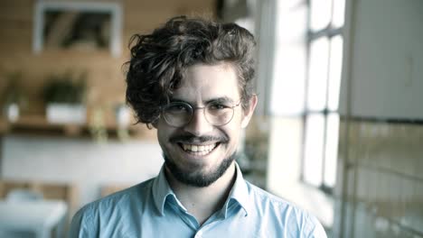 vista frontal de un joven con gafas sonriendo y guiñando el ojo