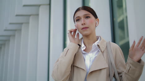 girl communicating wireless earbuds standing city street alone close up.