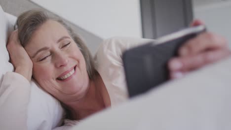 woman having a video chat on her smartphone in bed at home