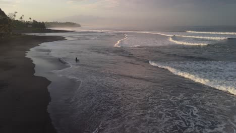 balian surfers beach with solo silhouetted surfer walking out to catch some tranquil waves