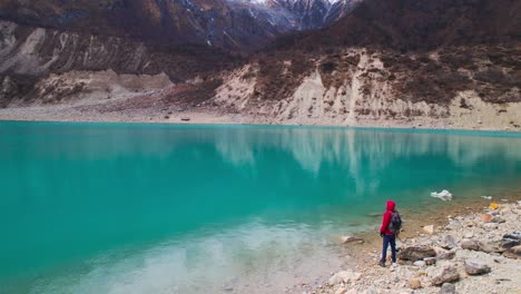 Drone-footage-shows-a-boy-in-a-red-jacket-enjoying-the-view-at-Birendra-Lake-on-the-Manaslu-Circuit-Trek-in-Nepal,-with-a-majestic-reveal-of-the-surrounding-landscape
