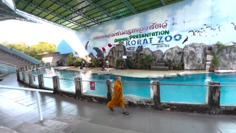 monk walks by sea lion exhibit at zoo