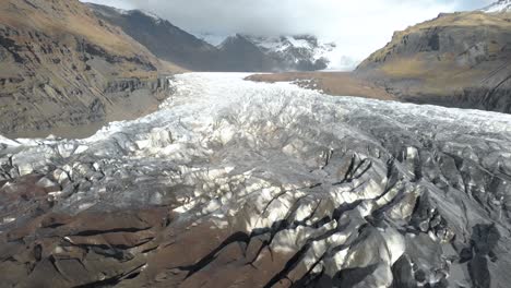 slow cinematic aerial shot flying towards the base of a glacier