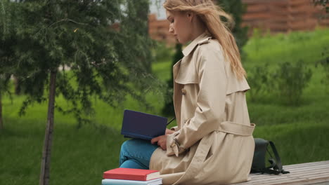 estudiante caucásica escribiendo en un cuaderno en el parque.