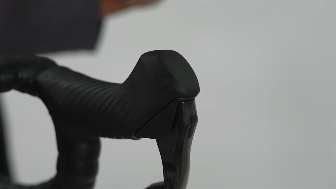 Close-up of a hand pressing a bicycle handlebar shifter