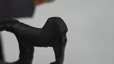close-up of a hand pressing a bicycle handlebar shifter
