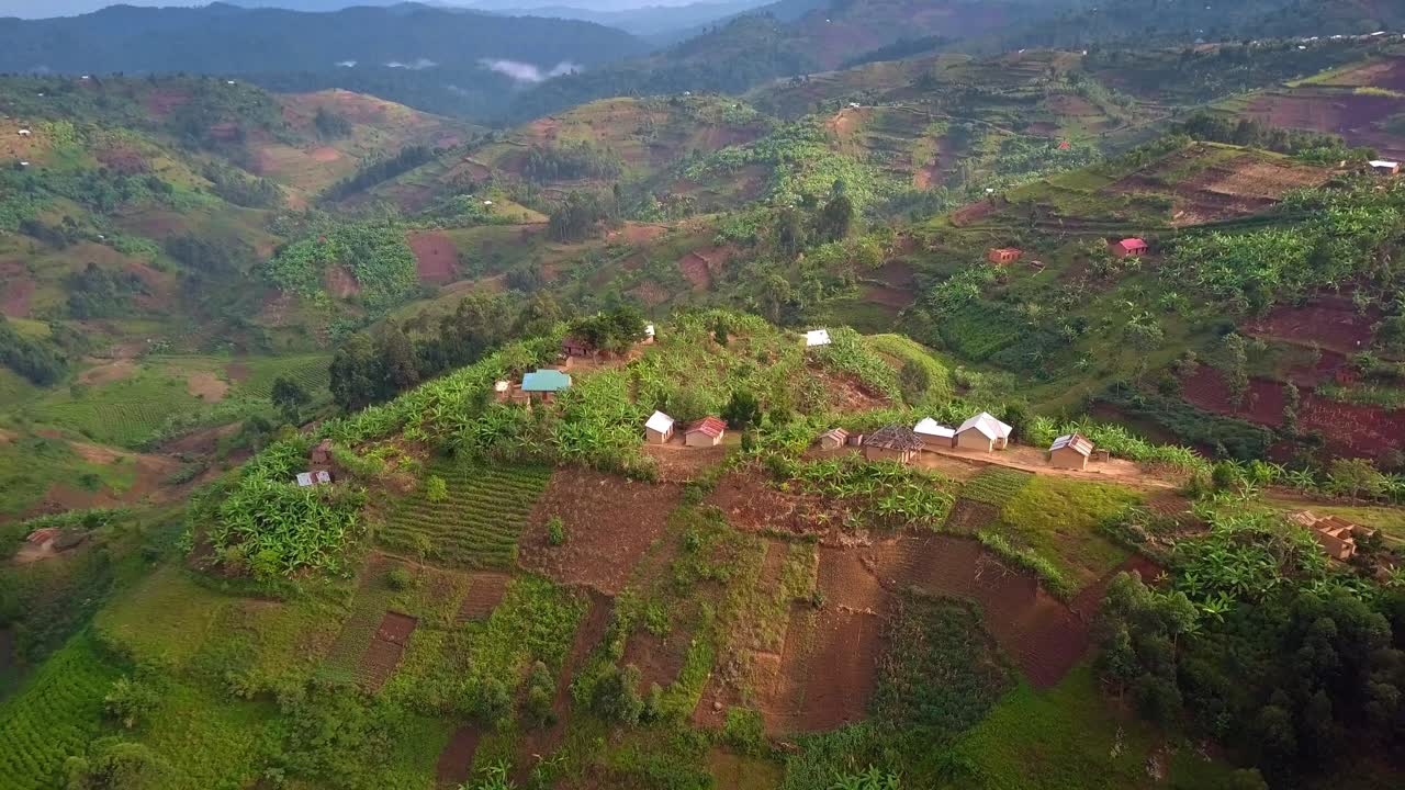Villaggio con case sparse su terreni agricoli collinari nel Distretto di Kanungu, vicino al Parco Nazionale impenetrabile di Bwindi, Uganda, che mostra un paesaggio di piccola agricoltura, avvicinamento con drone.