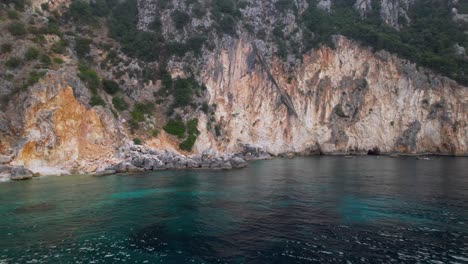 ladera rocosa de colinas y cuevas naturales en la costa del mediterráneo en albania, bañada por agua de mar esmeralda
