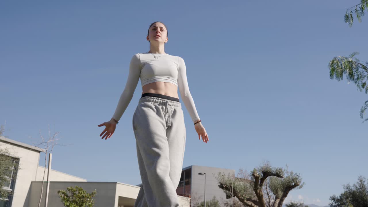 Young woman performing parkour acrobatics in urban park