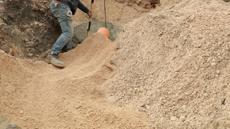 laborer compacts the soil around the orange pvc pipe at roadwork in portugal