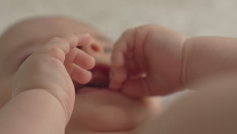 Closeup-happy-baby-boy-face,-hands,-soft-light-in-white-bed