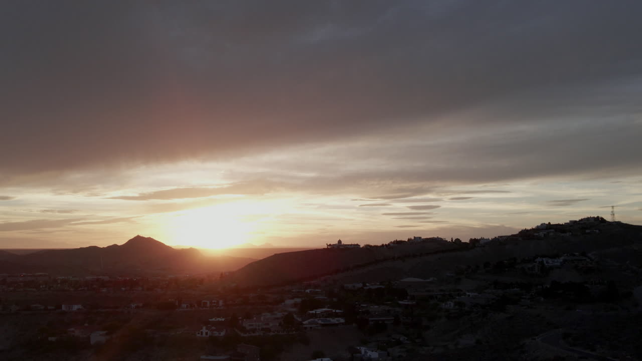 inclinación aérea hacia abajo del dramático el paso, puesta de sol con edificios de silueta y horizonte
