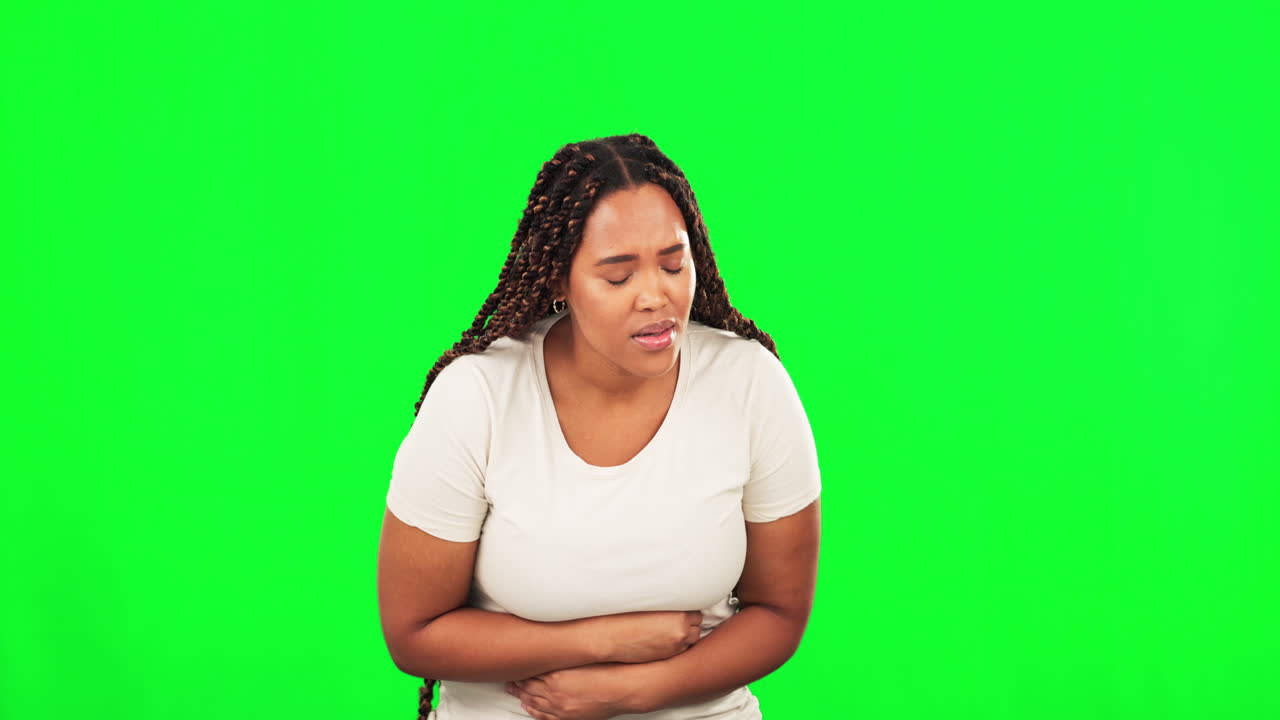 Donna di colore malata con mal di stomaco su sfondo verde in studio
