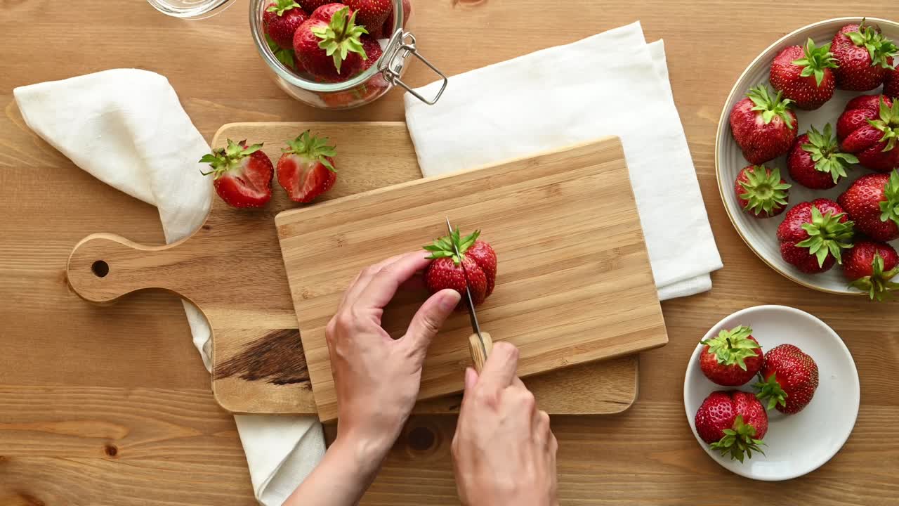 mujer anónima cortando fresas fresas en la tabla de cortar