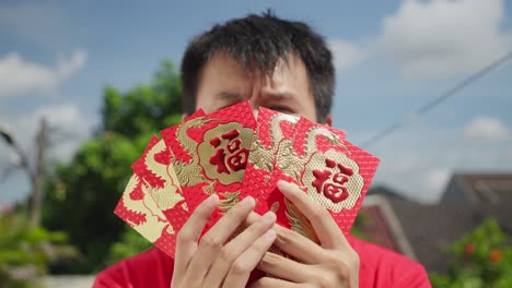 asian male showing to camera several hongbao in hand