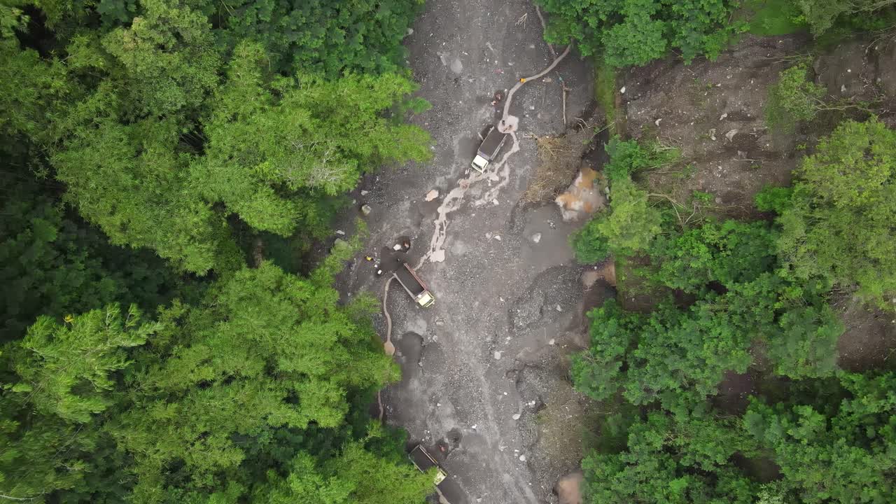 vista aérea, flujo de río de lava fría del monte merapi y camiones visibles y mineros de arena en movimiento