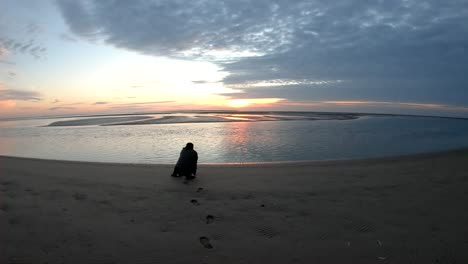 Drone-aerial-footage-of-a-man-taking-photographs-of-the-sunset-by-the-ocean