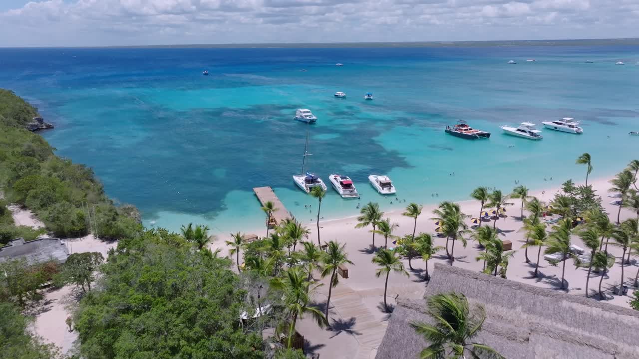 Barche ormeggiate e persone che si godono la stagione estiva sulla spiaggia dell'isola tropicale di Catalina e acque turchesi nella Repubblica Dominicana.