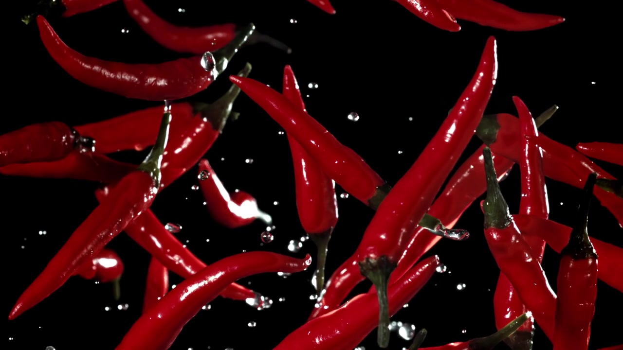 Red Chili Peppers Flying in Slow Motion with Water Droplets