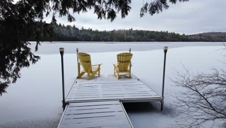 lake clermoustier, petit-chertsey, canada - a serene winter landscape with its frozen waters and snow-covered docks surrounded by tranquil woods - drone flying forward