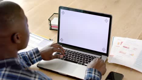 Hombre-Afroamericano-Sentado-En-La-Mesa-Usando-Una-Computadora-Portátil-Con-Espacio-Para-Copiar-En-La-Pantalla-En-Casa,-Cámara-Lenta