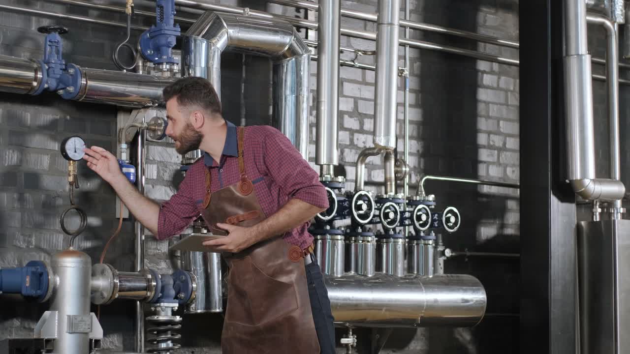 un joven cervecero con un delantal de cuero supervisa el proceso de fermentación de la cerveza en una fábrica de cerveza moderna