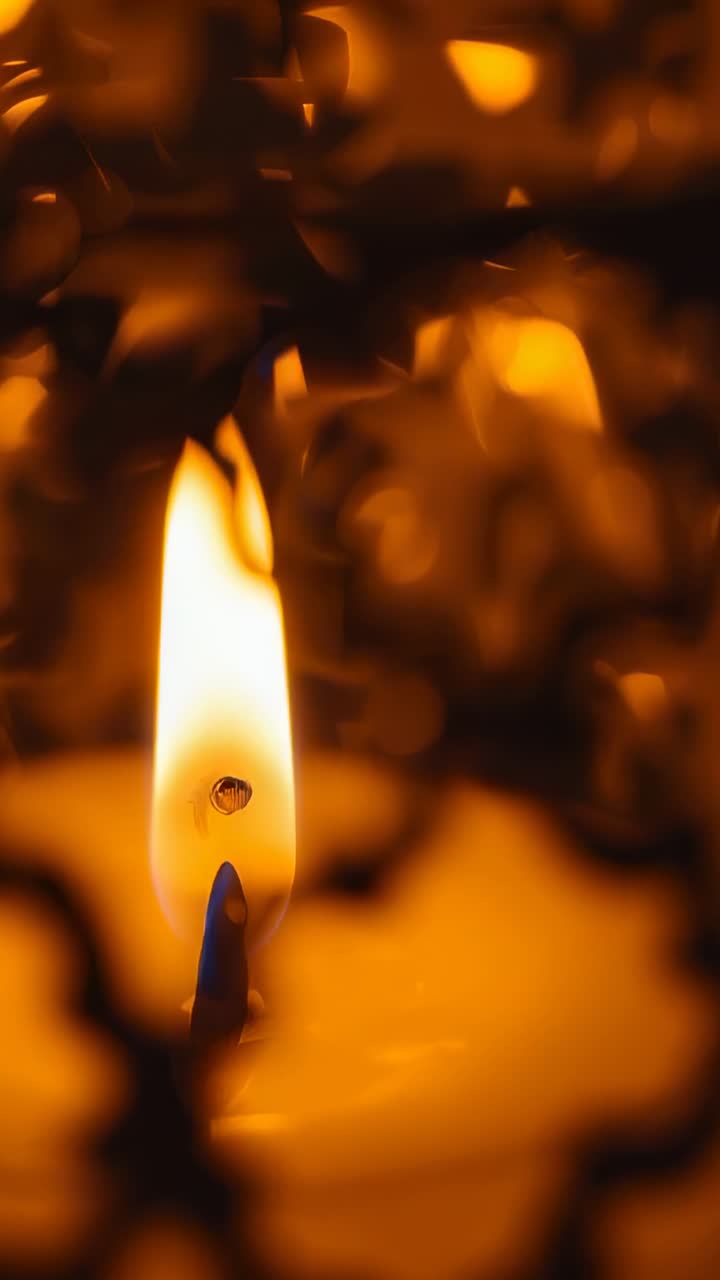 Vertical video: Flickering flame leaning from breeze behind lattice indoors, droplet melting