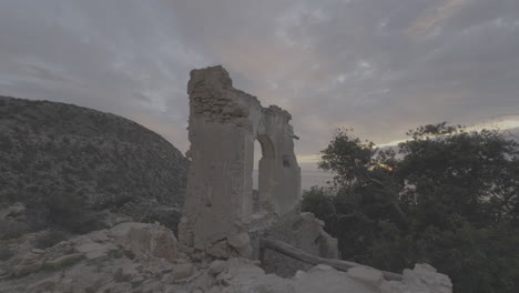 ruined arch in mountainous landscape at sunrise/sunset