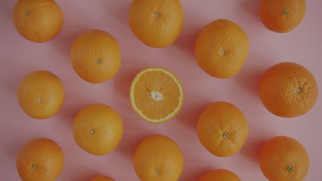 oranges and a hand on a pink background