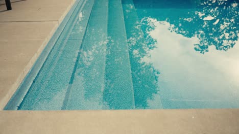 Agua-Y-Pasos-Dentro-De-Una-Piscina-En-El-Patio-Trasero-Con-El-Reflejo-De-Los-árboles-Y-La-Luz-Del-Sol-En-El-Agua