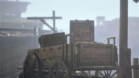 an old wooden wagon sits in an abandoned western town.