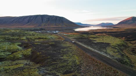 Luftaufnahme-Eines-Weißen-Land-Rovers,-Der-Auf-Einer-Einsamen-Straße-Durch-Die-Isländische-Berglandschaft-Fährt