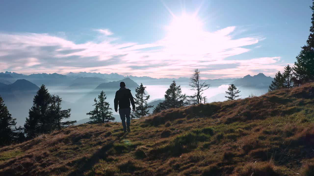 chico persona caminando a cámara lenta en una cresta de montaña mirando hacia el hermoso paisaje de montaña con lago cubierto de niebla soleados alpes suizos rigi
