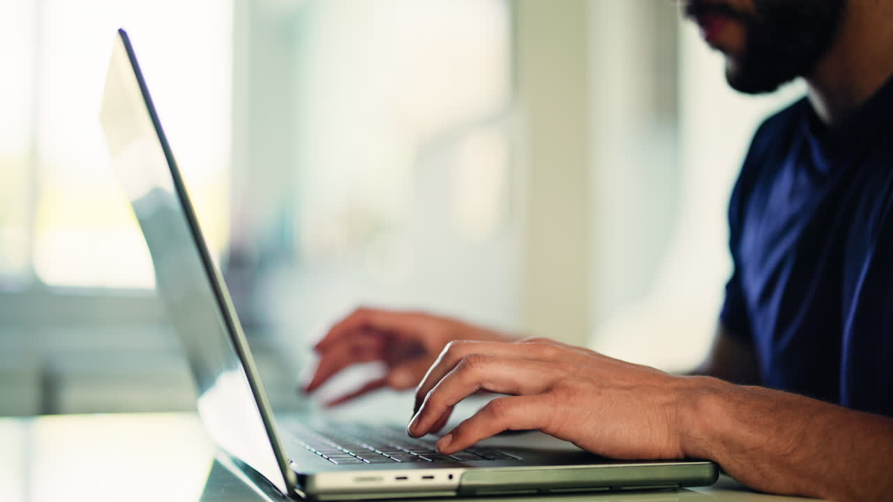Close-up of Man's Hands Typing on Laptop Keyboard