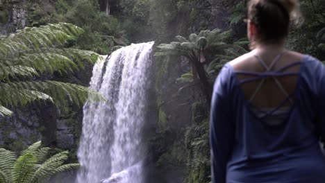 still shot of girl admiring flowing waterfall